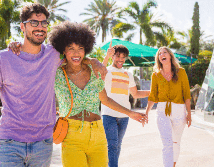 Four people talking and laughing in a location with palm trees.