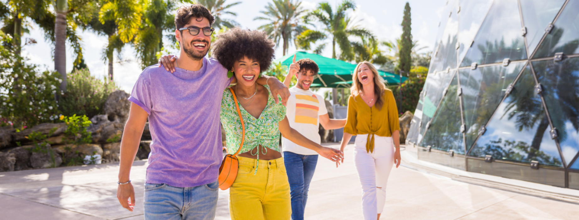 Four people talking and laughing in a location with palm trees.