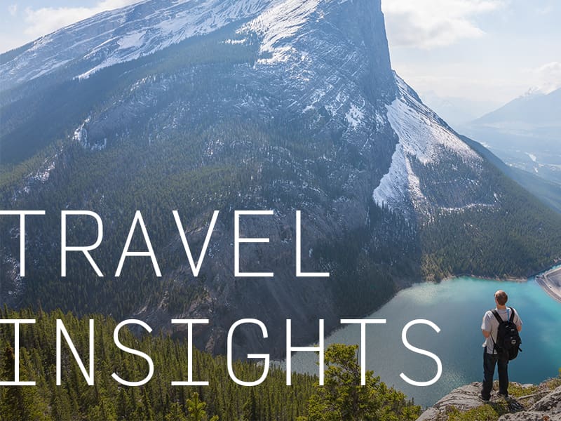 A backpacker overlooking a mountain and a lake with the caption "Travel Insights".
