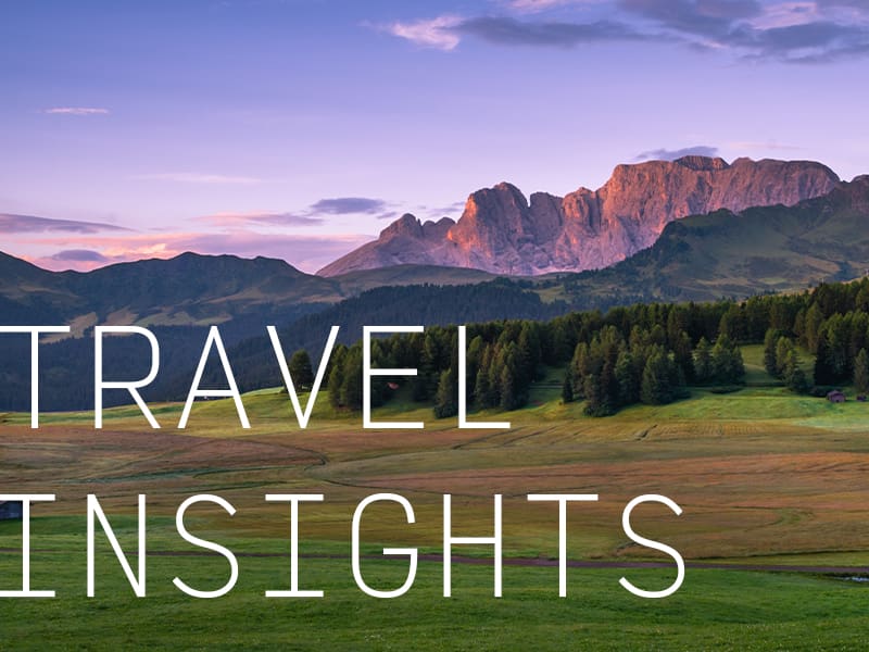 A landscape of rocky plateaus during a purple sunset with the caption "Travel Insights".