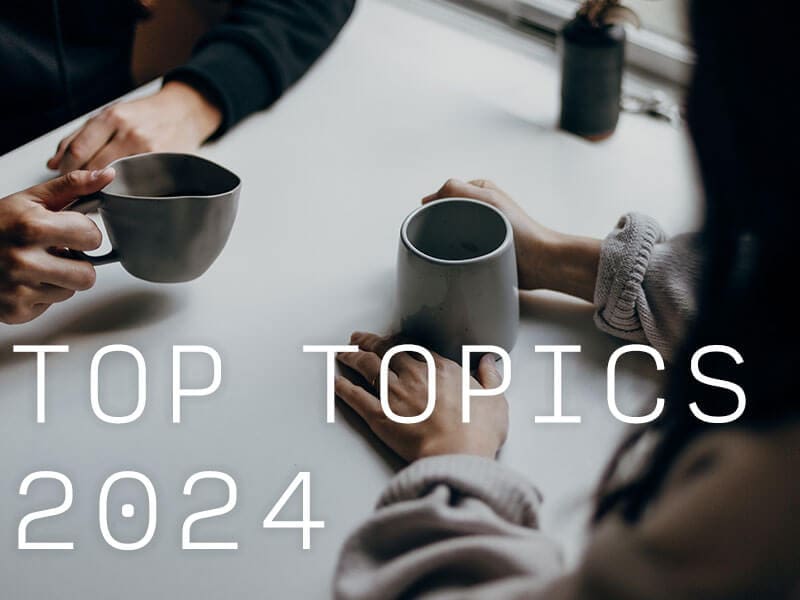Two people's hands holding coffee mugs on top of a table.