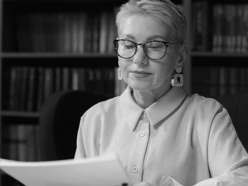 An older women with glasses reading a piece of paper.
