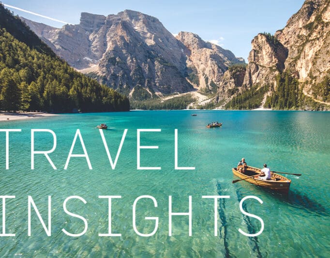 Kayakers in a clear lake surrounded by a mountain range with the caption "Travel Insights".